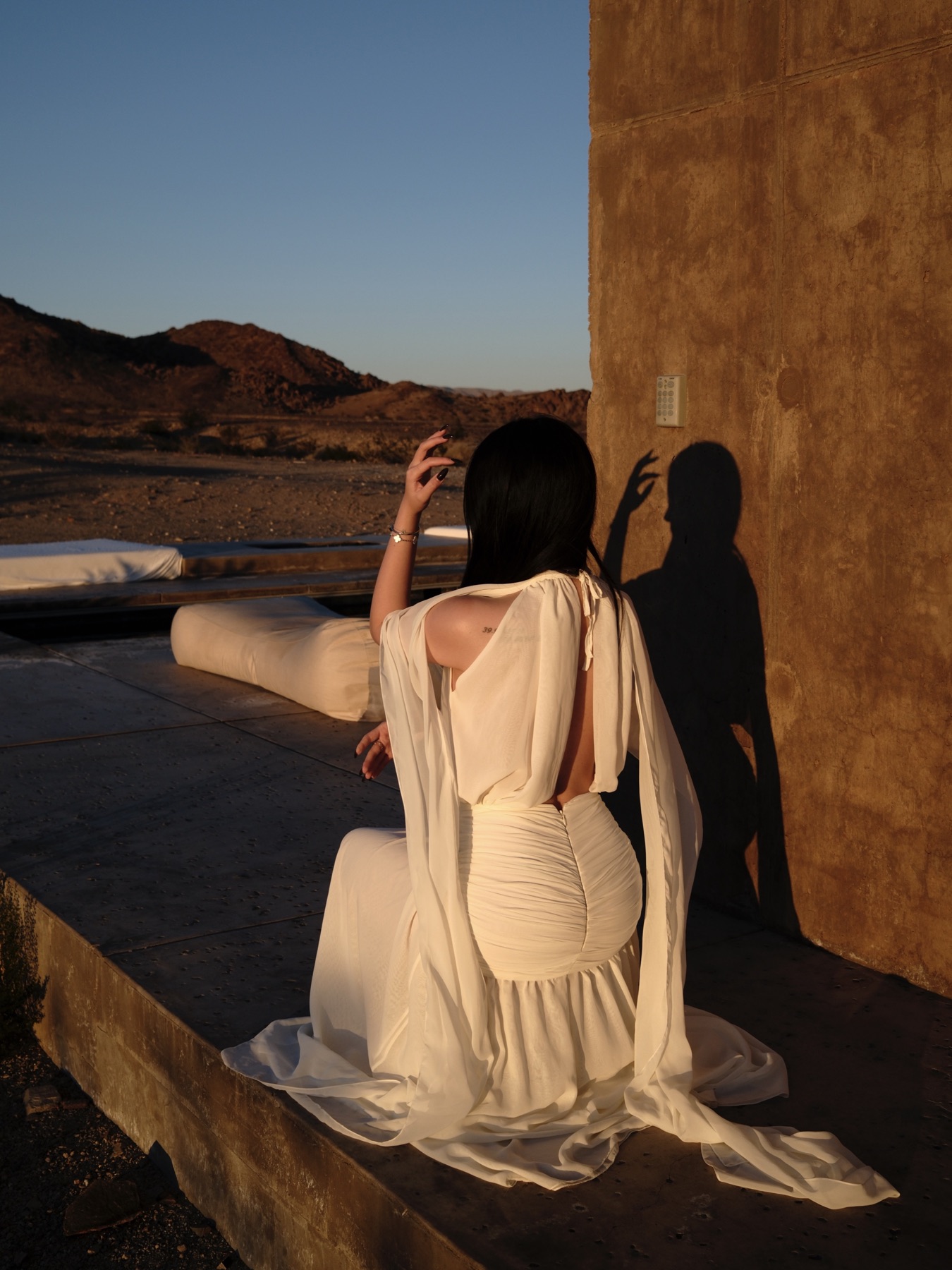 White dress in desert light against a warm architectural wall