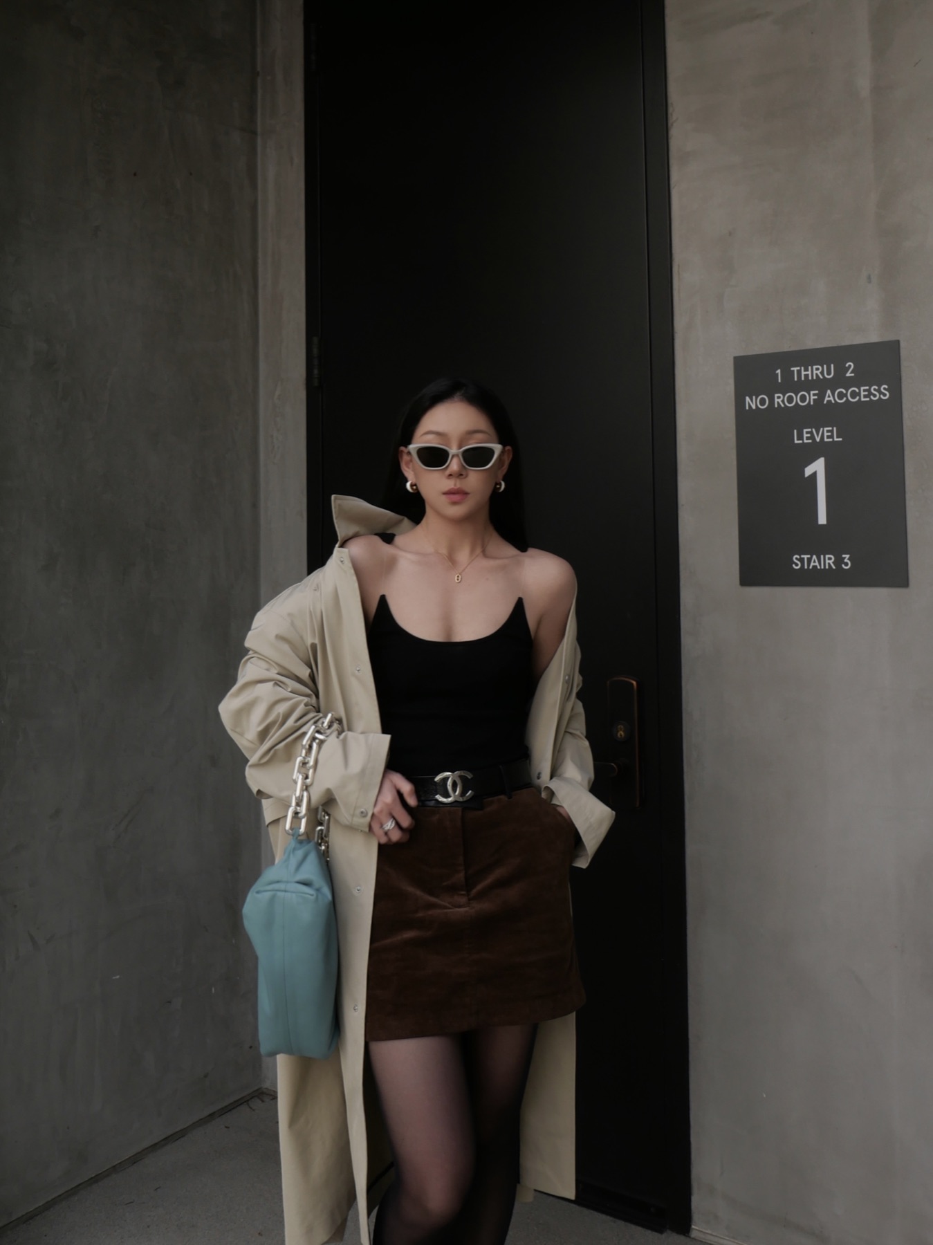 PHOEBE.L in sunglasses framed by a concrete doorway