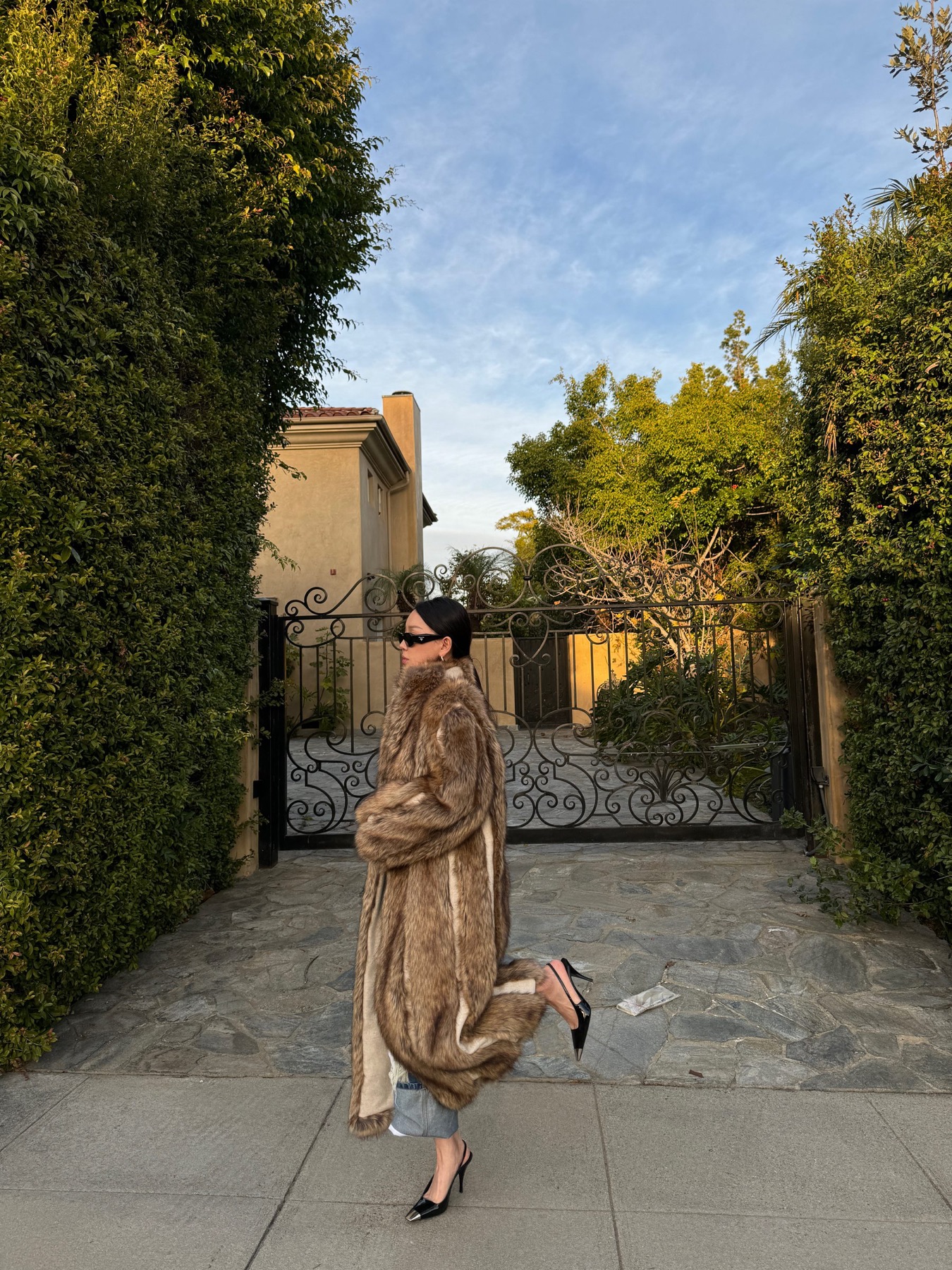 Belted trench in motion along a garden path